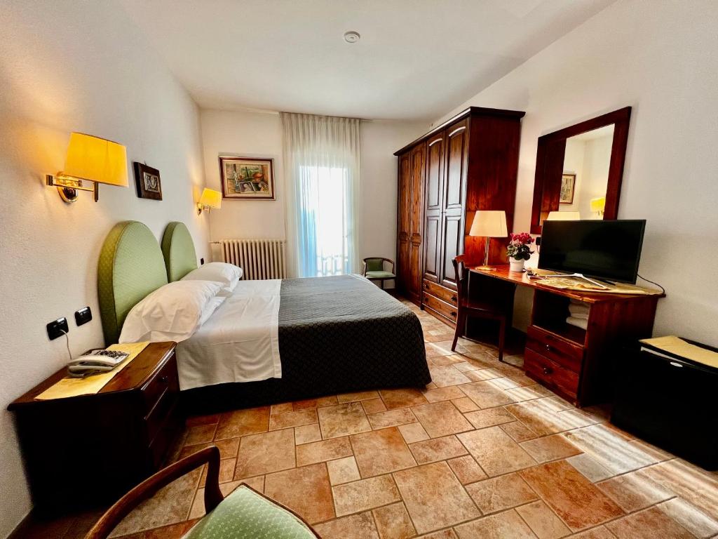 Habitación de hotel con cama, escritorio y TV. en Aurora en Castione della Presolana