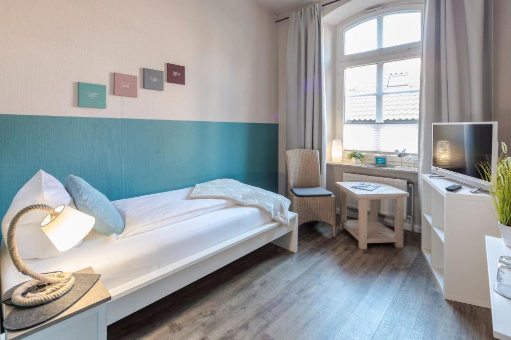 a bedroom with a bed and a desk and a tv at Gästehaus Von Herzen in Lauenburg