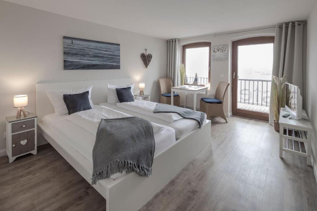 a white bedroom with a large bed and a desk at Gästehaus Von Herzen in Lauenburg