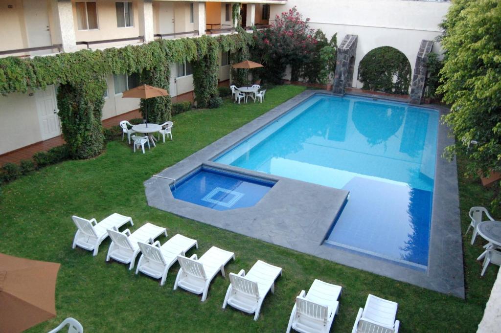 a swimming pool with white chairs and a yard with at Real de Minas San Luis Potosi in San Luis Potosí