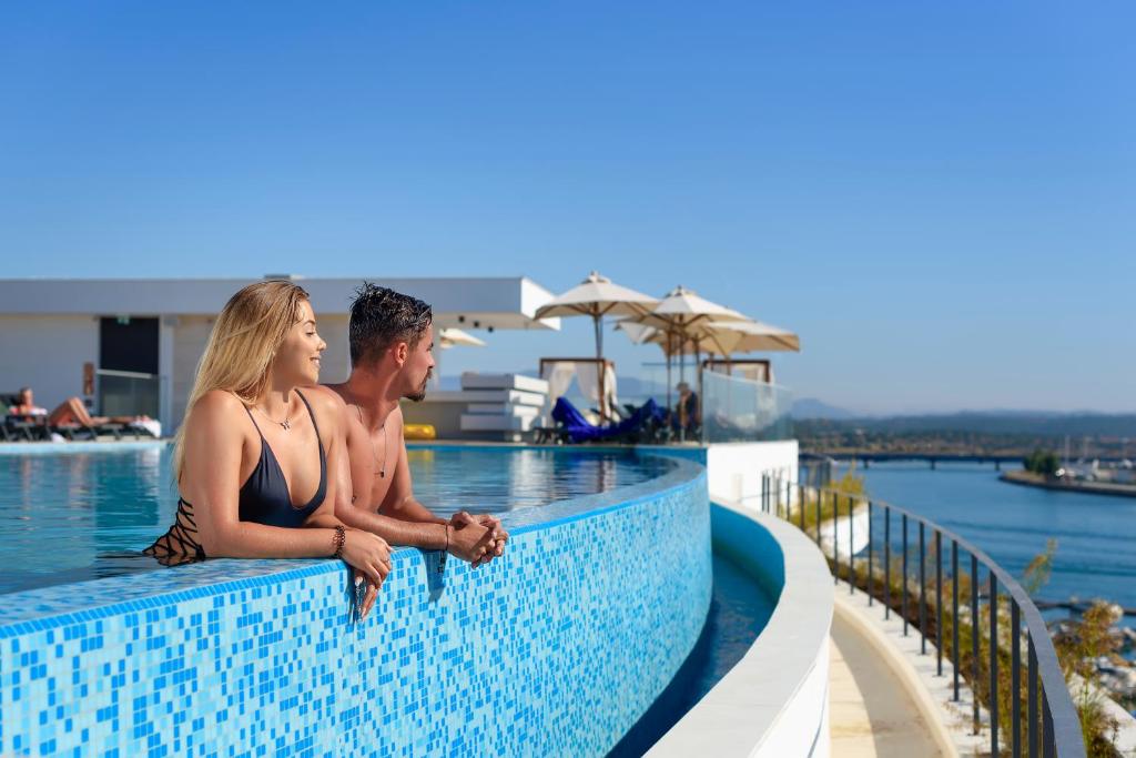 
two women are sitting on a balcony overlooking the ocean at Jupiter Marina Hotel - Couples & Spa in Portimão
