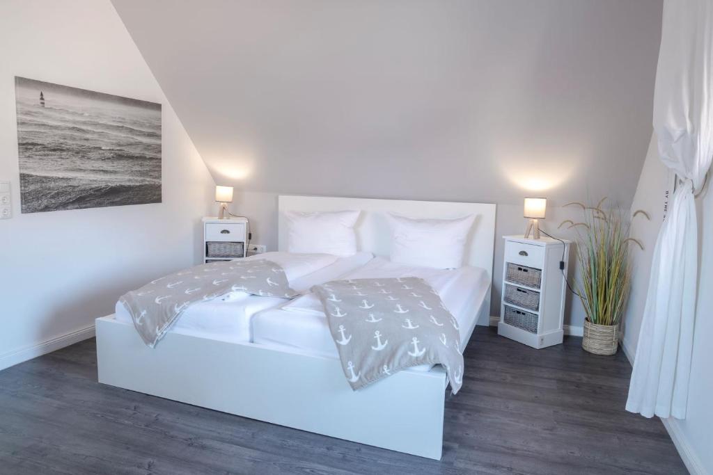 a white bedroom with a white bed and two night stands at Gästehaus Von Herzen in Lauenburg