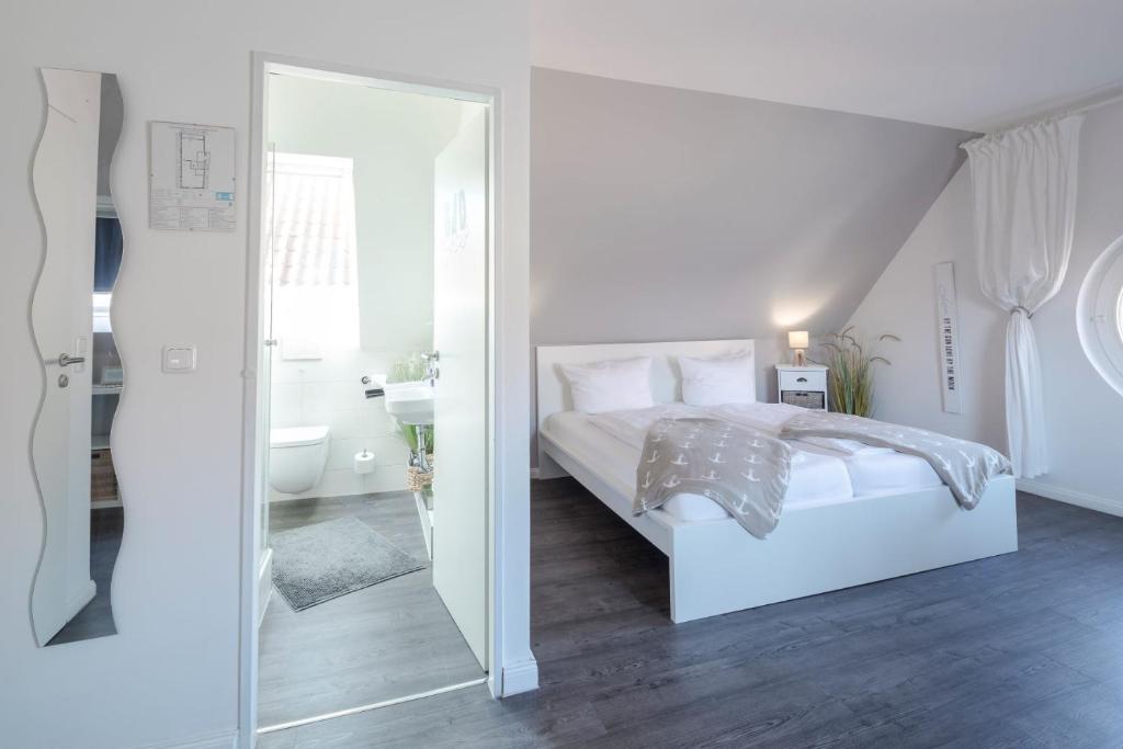 a white bedroom with a bed and a mirror at Gästehaus Von Herzen in Lauenburg