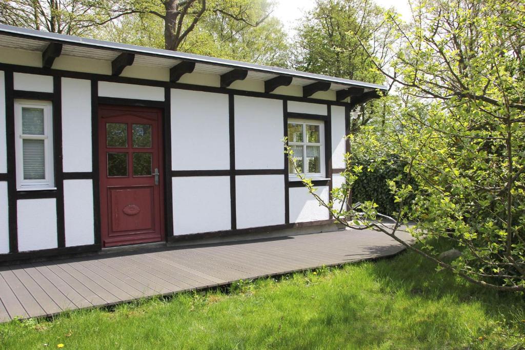 ein kleines Cottage mit einer roten Tür auf einer Terrasse in der Unterkunft Am Prerowstrom in Prerow