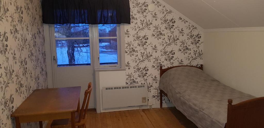 a bedroom with a bed and a table and a window at Forsnäsgården B&B in Stora Skedvi