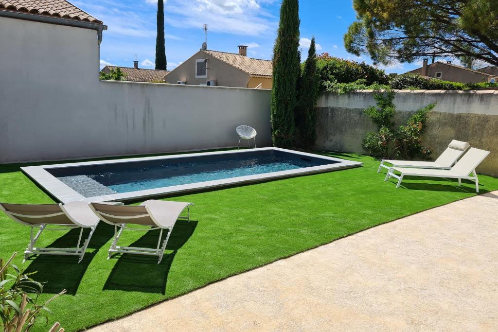 une cour avec une piscine, des chaises et de la pelouse dans l'établissement Villa Lisa - piscine chauffée, à LʼIsle-sur-la-Sorgue
