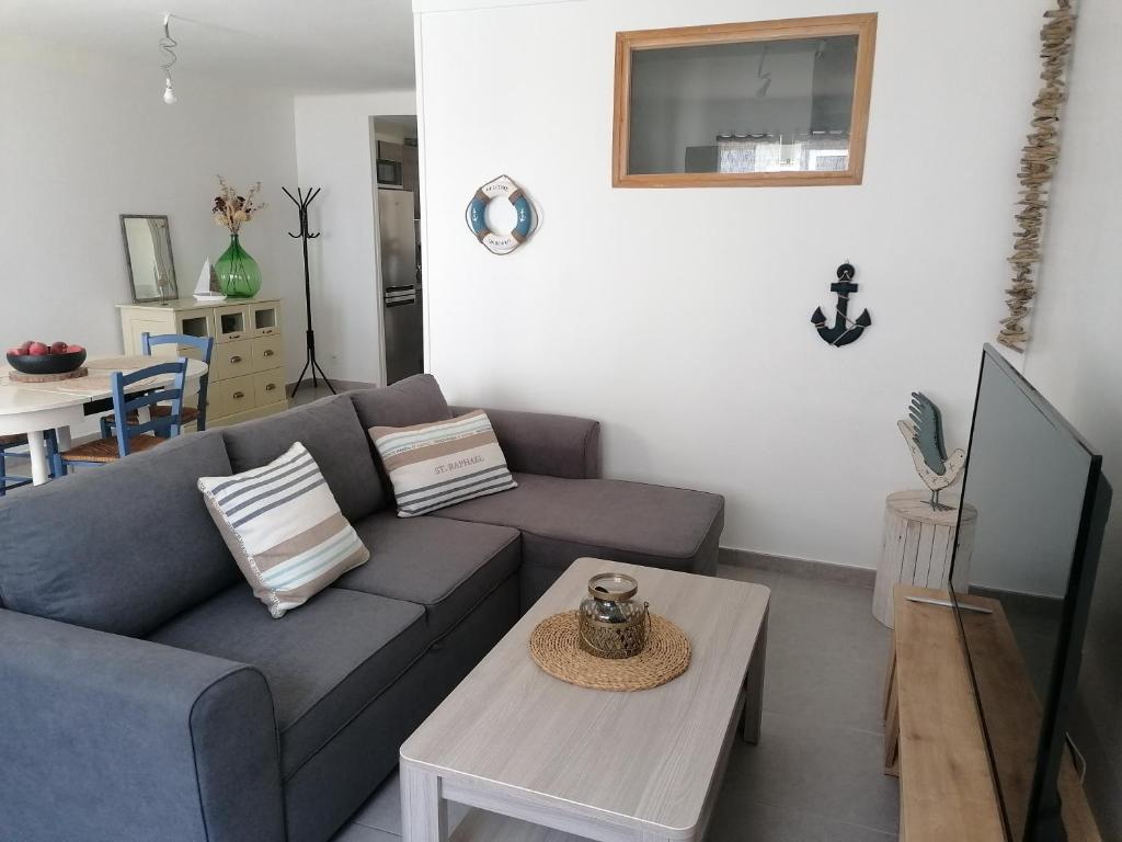 un salon avec un canapé bleu et une table dans l'établissement Appartement SÈTE LA CORNICHE - 4 PERSONNES, à Sète