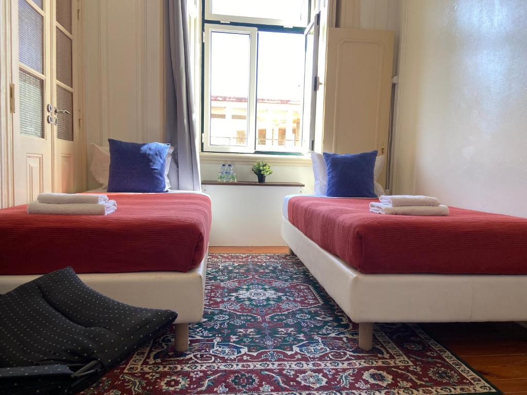 two beds in a room with a window at PALMA 3 BEDROOM APARTMENTS-a in Lisbon