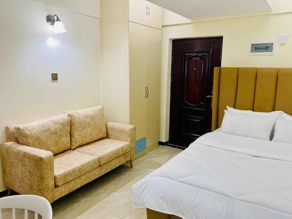 ein Schlafzimmer mit einem Bett, einem Sofa und einem Stuhl in der Unterkunft Dala Studio - Denis Pritt Road in Nairobi