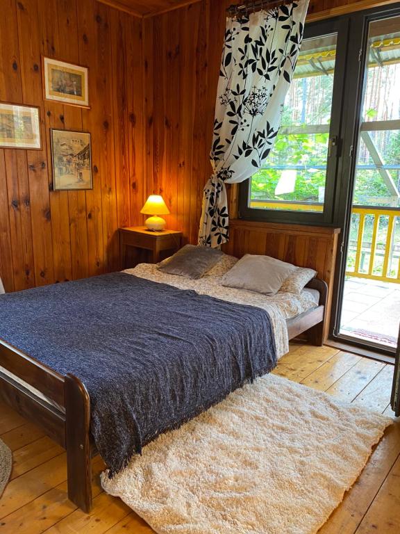 een slaapkamer met een bed in een kamer met houten wanden bij Leśny Czar in Serock