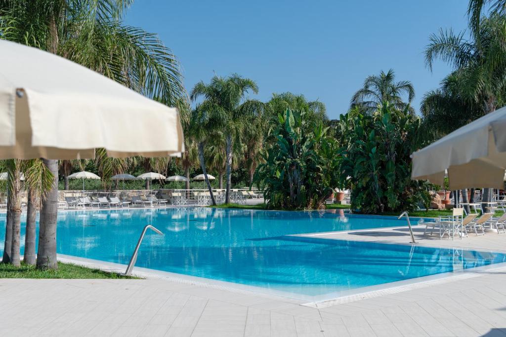 una piscina en un complejo con sillas y sombrillas en Vascellero Club Resort, en Cariati