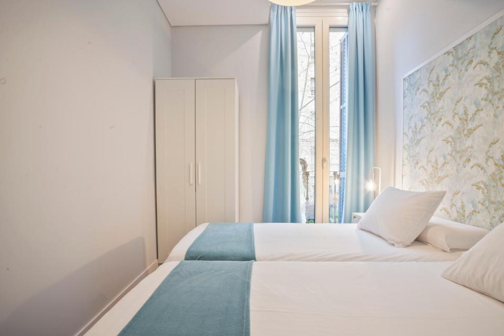 a bedroom with a white bed with blue curtains at Barcelona Eixample in Barcelona