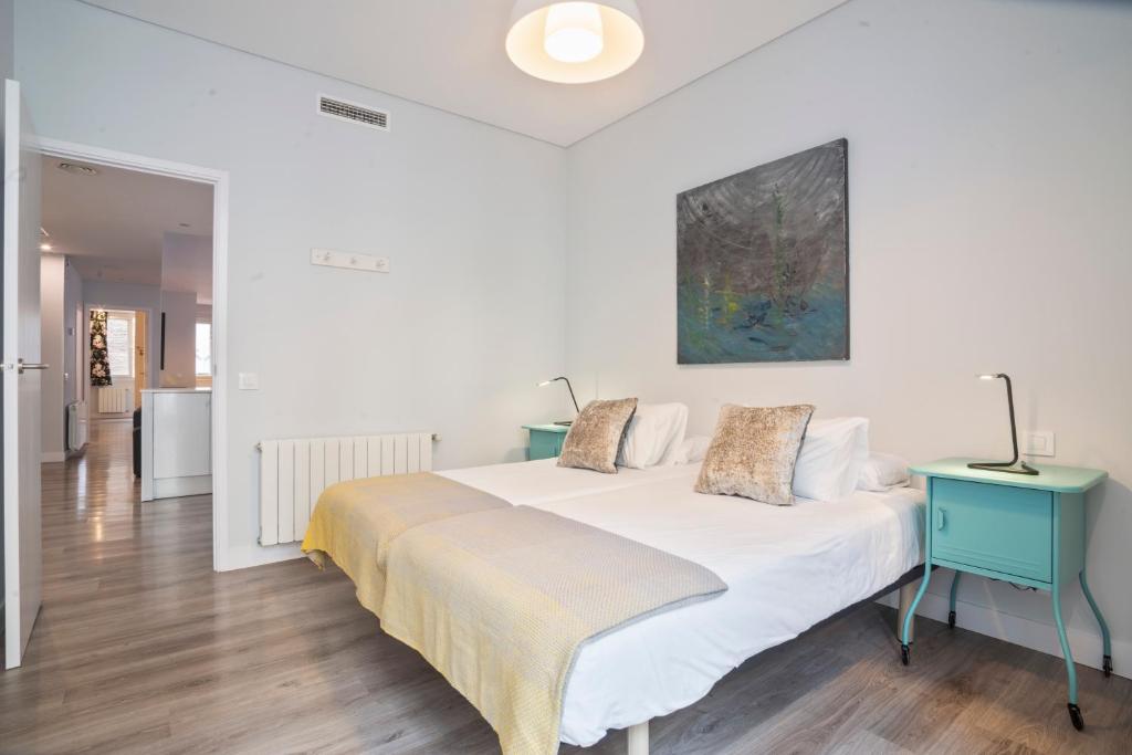 a white bedroom with a bed and a blue table at Barcelona Eixample in Barcelona