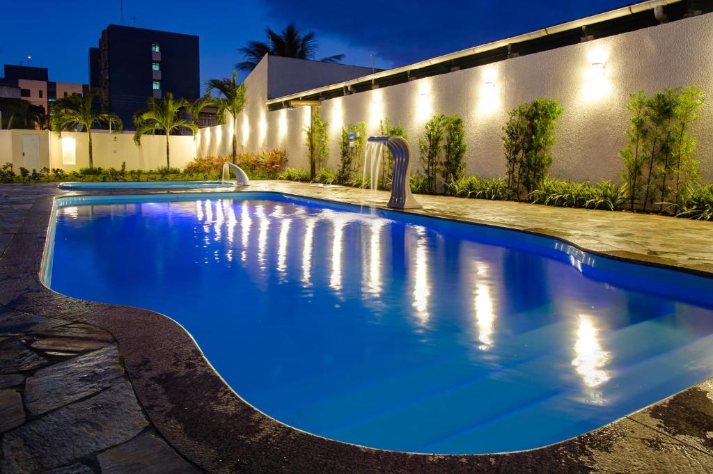 uma piscina com água azul em frente a um edifício em Marezzi Hotel Aracaju em Aracaju