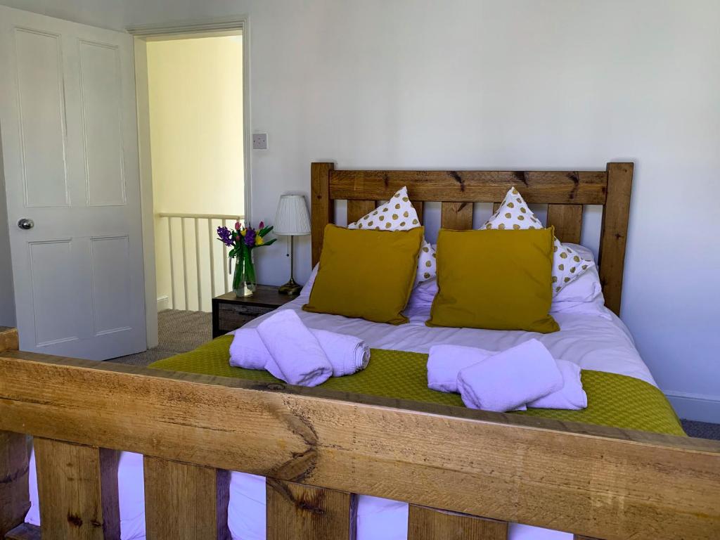 ein Schlafzimmer mit einem Holzbett mit gelben und weißen Kissen in der Unterkunft Park Crescent Lodge - Quaint Victorian Home With Free Parking in York