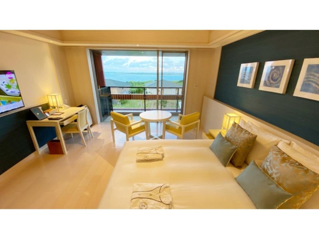 UechiにあるMiyakojima Kurima Resort Seawood Hotel - Vacation STAY 16234vの大型ベッド、テーブル、窓が備わる客室です。