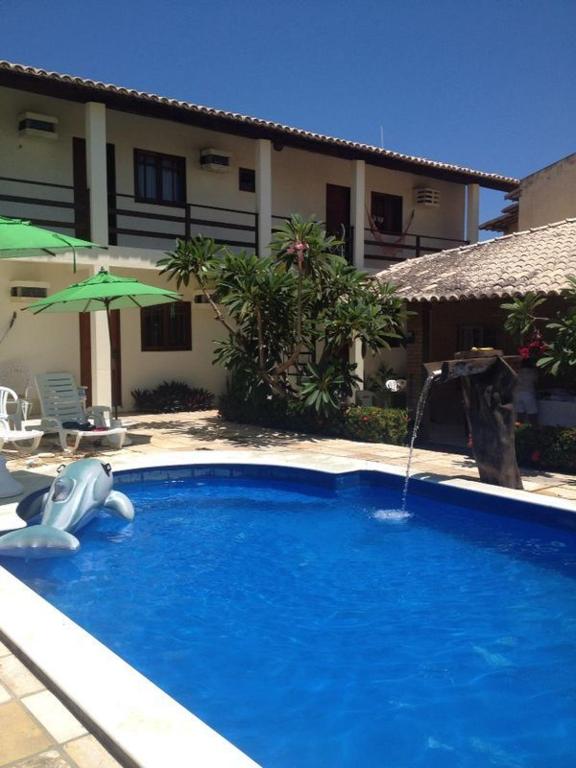 a swimming pool with a water slide in front of a house at Pousada Villa Joia in Barra de São Miguel