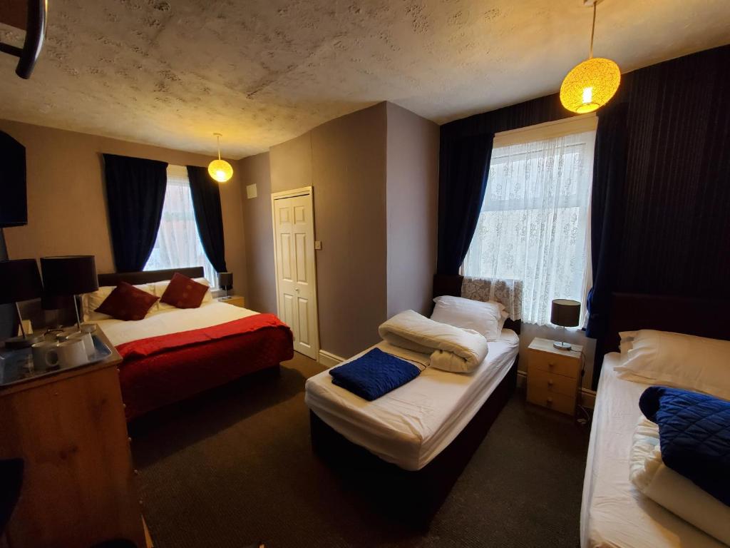 a hotel room with two beds and two windows at the cumbrian hotel in Blackpool
