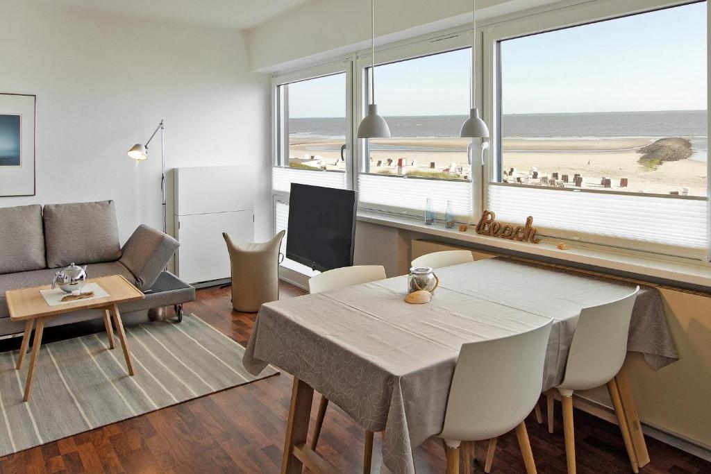 een woonkamer met een eettafel en uitzicht op het strand bij Haus Panorama Haus Panorama 12 in Wangerooge