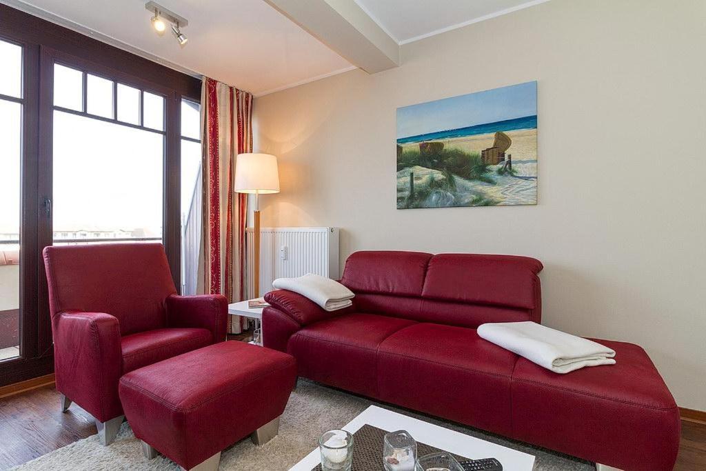 ein Wohnzimmer mit einem roten Sofa und zwei Stühlen in der Unterkunft Urlaubsräume am Meer Urlaubsräume am Meer 3-14 in Fulgen