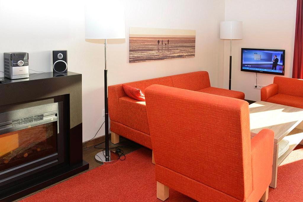 ein Wohnzimmer mit 2 orangenen Stühlen und einem TV in der Unterkunft Resort Deichgraf Resort Deichgraf 27-13 in Wremen