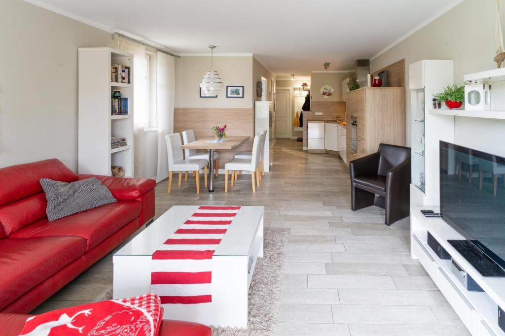 ein Wohnzimmer mit einem roten Sofa und einem Tisch in der Unterkunft Ferienwohnung Strandgut - Kavelweg 9 - Zingst in Zingst