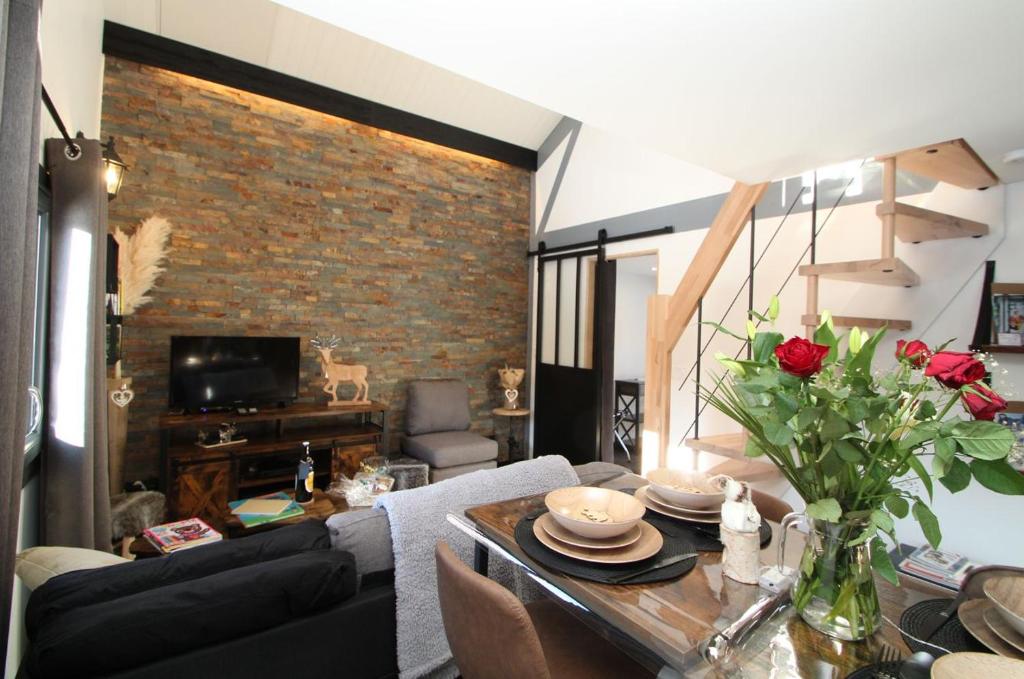 a living room with a table and a brick wall at LE CHALET DES MERVEILLES in Les Achards