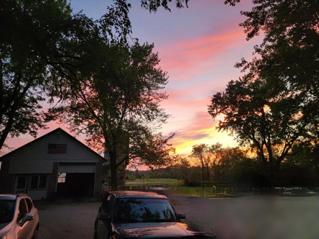 una puesta de sol con dos coches estacionados frente a un granero en Farmhouse attached apartment, en Old Mill Creek