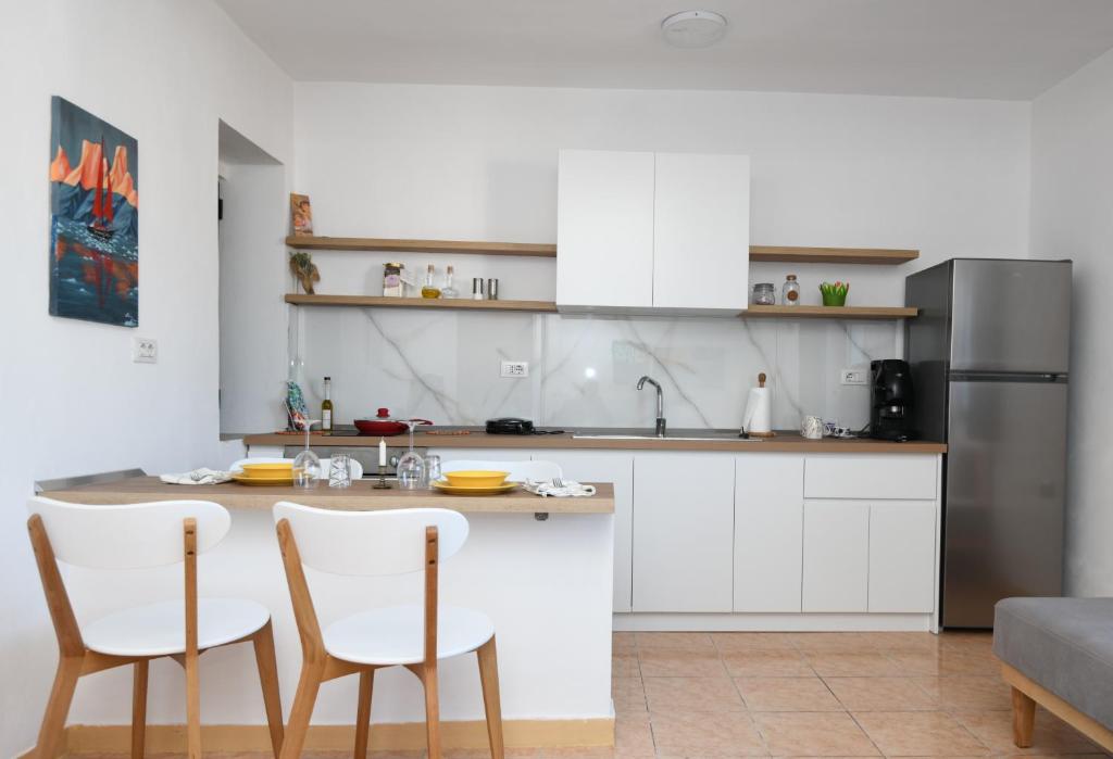 uma cozinha com armários brancos e uma mesa e cadeiras em Rondine Studio Apartment em Tirana