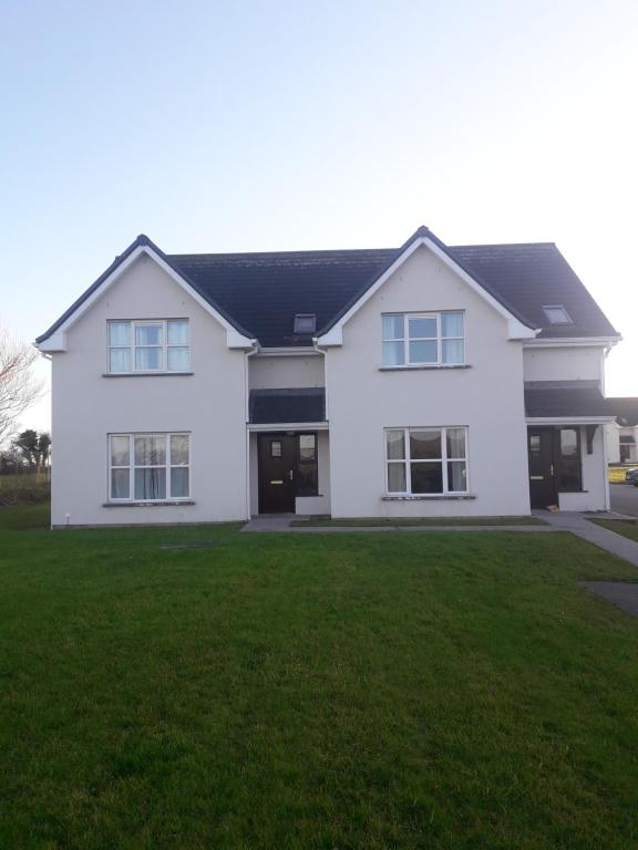 a white house with a green lawn at 4 bedroom home by the sea in Cork