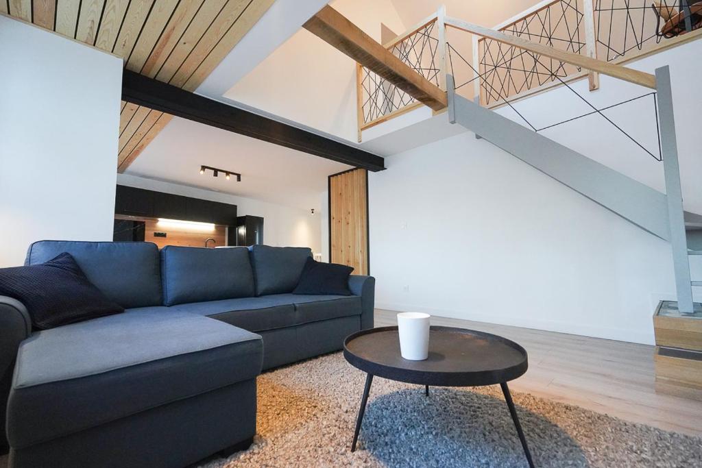 sala de estar con sofá azul y mesa en La Villa Bérénice - "Le Duplex" en coeur de ville, en Saint-Amand-les-Eaux