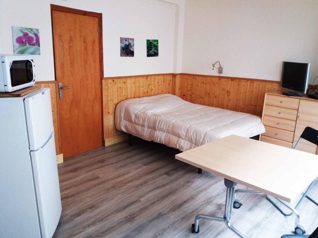 a small room with a bed and a desk and a microwave at Rosesapparts Estudios & Parking in Roses