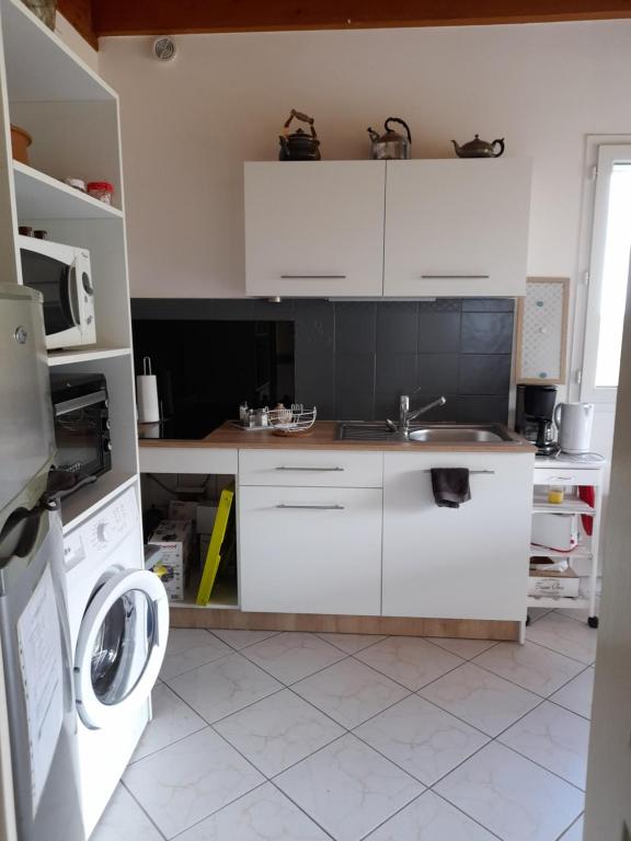 a white kitchen with a sink and a washing machine at Ô ptit gîte d&#39;Ogenne in Ogenne-Camptort