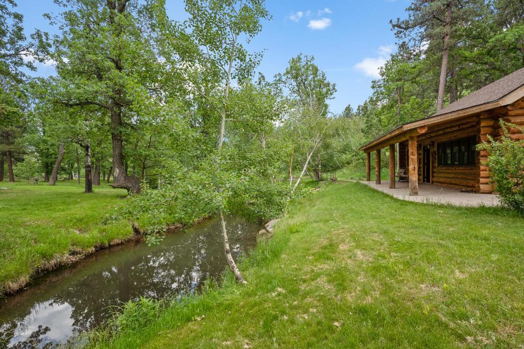 a log cabin with a stream next to a building at The Cabin At Brookview Ask About Our Fun Bundles in Rapid City