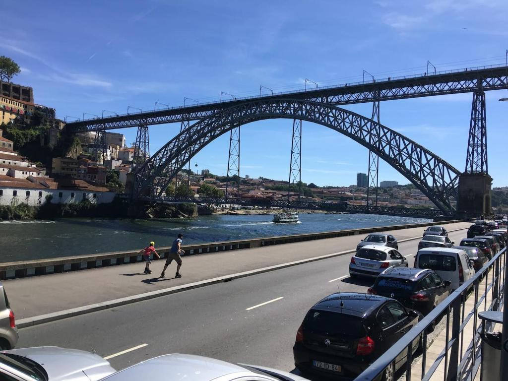 un puente sobre un río con coches aparcados en la carretera en Ribeira Flats MyGod, en Oporto