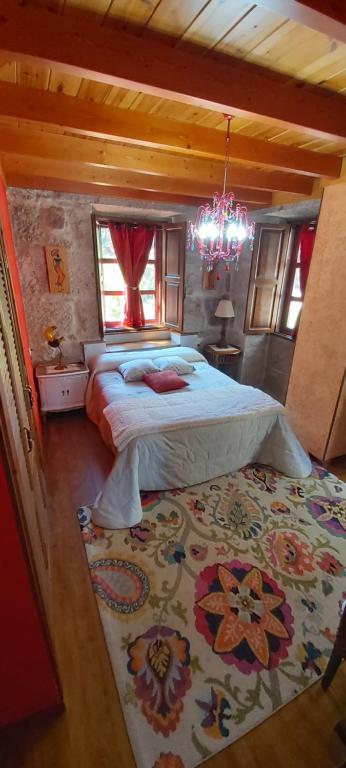 a bedroom with a large bed and a chandelier at A Casa da Carballa in Ponteareas