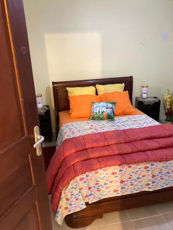 um quarto com uma cama com almofadas laranja em Le refuge privatif de Julie em Basse-Pointe
