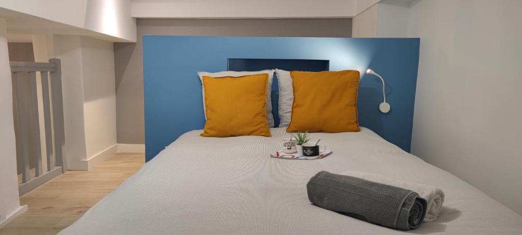 une chambre avec un lit avec des oreillers jaunes dans l'établissement Duplex cosy - Gare - Hyper centre - WIFI, à Angers