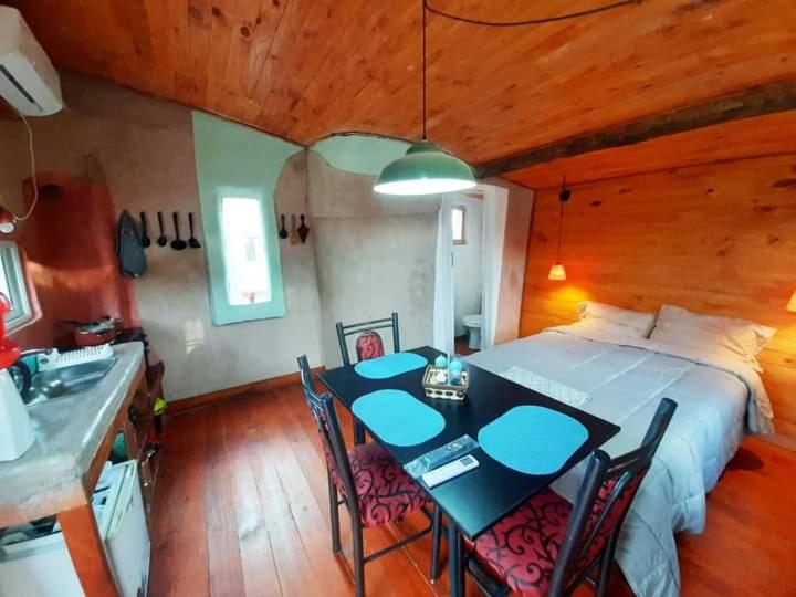 a bedroom with a bed and a table and chairs at ECOCABAÑAS CERRO ARKO in Mendoza