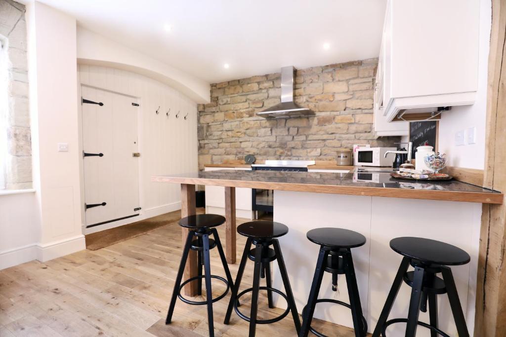 a kitchen with bar stools and a counter top at Stable Cottage in Pateley Bridge