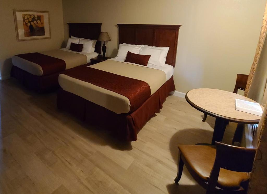 a hotel room with two beds and a table at Homestead Motel in Branson