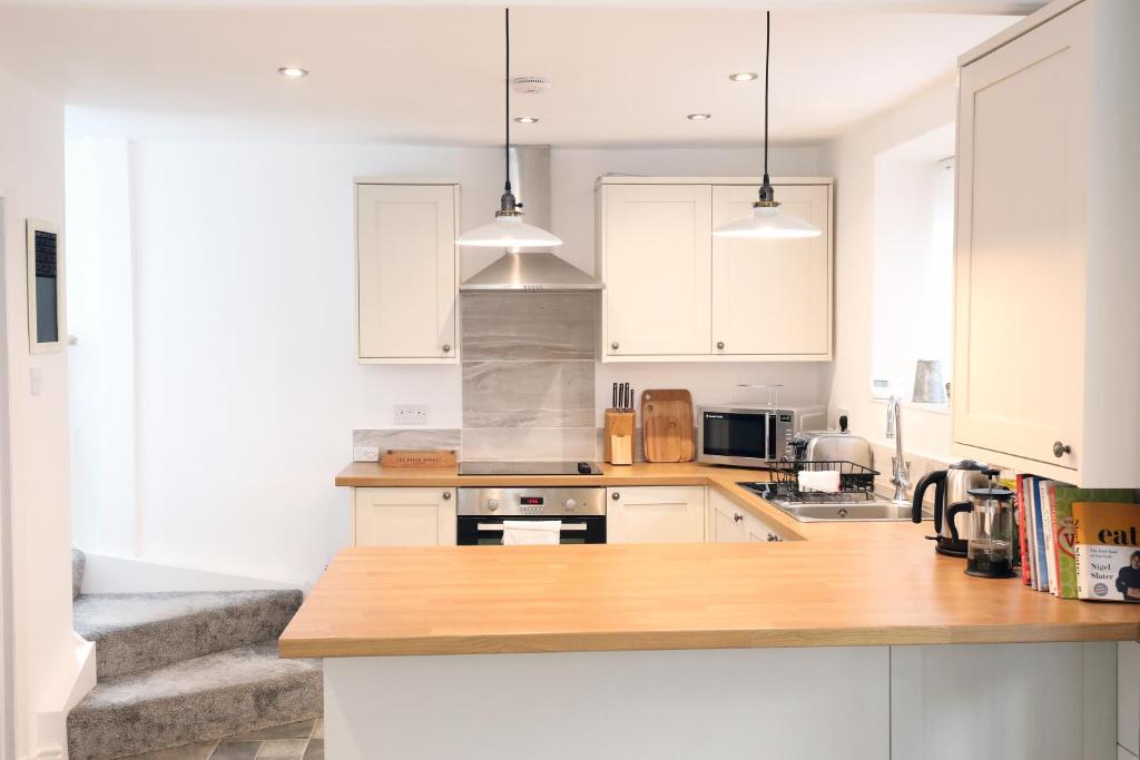 cocina con armarios blancos y encimera de madera en Willow Cottage en Pateley Bridge