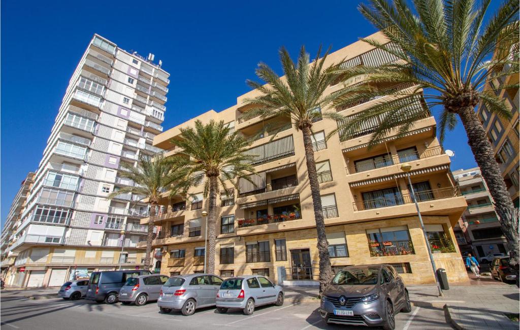 un bâtiment avec des palmiers et des voitures garées dans un parking dans l'établissement 4 Bedroom Lovely Apartment In Santa Pola, à Santa Pola