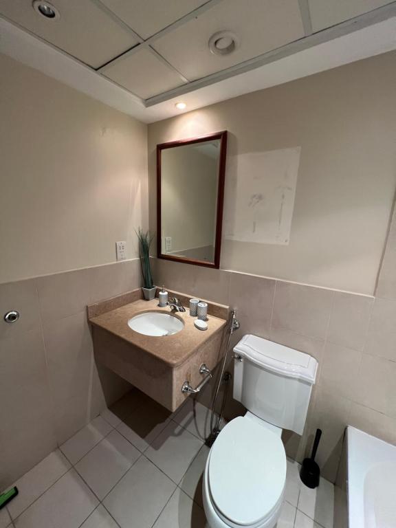 uma casa de banho com um WC, um lavatório e um espelho. em بِيُوتات الرفآه - ستوديو بإطلالة بحرية em King Abdullah Economic City