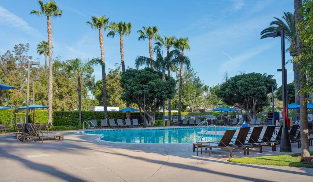 una piscina en un complejo con sillas y palmeras en Sonesta ES Suites Anaheim Resort Area en Anaheim