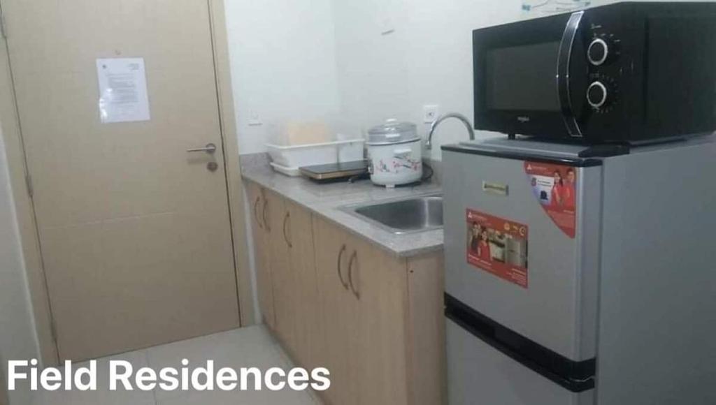 uma pequena cozinha com frigorífico e micro-ondas em Field Residences em Manila