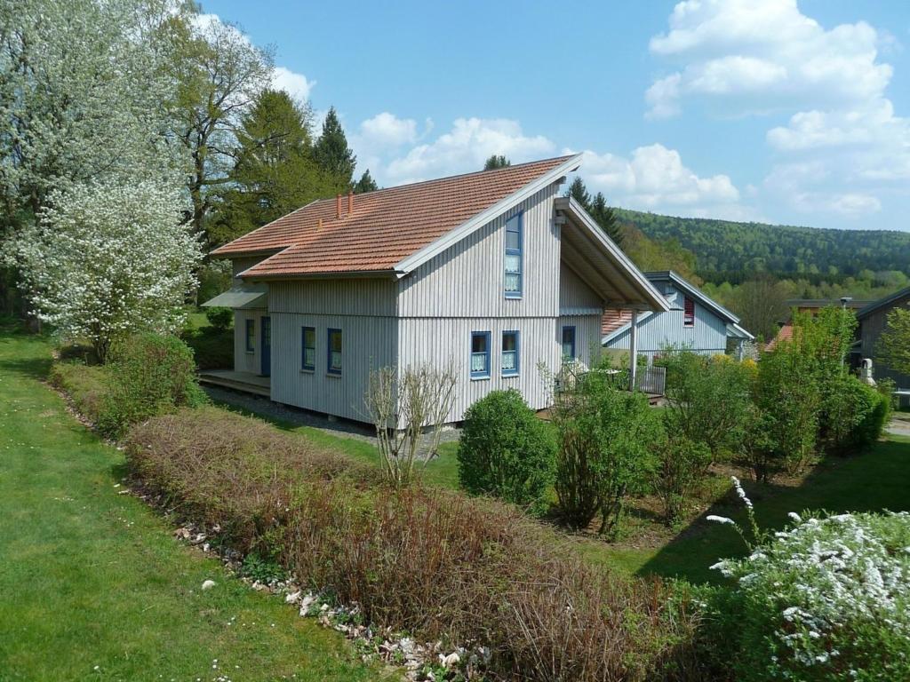 uma pequena casa branca com um telhado vermelho em Ferienhaus Nr 14A2, Feriendorf Hagbügerl, Bayr Wald em Waldmünchen