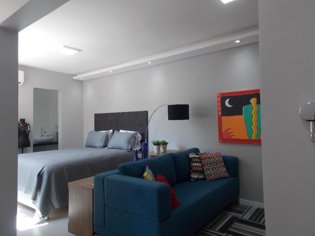 um quarto com uma cama e um sofá azul em Apt excelente local Consulado/Iguatemi em Porto Alegre