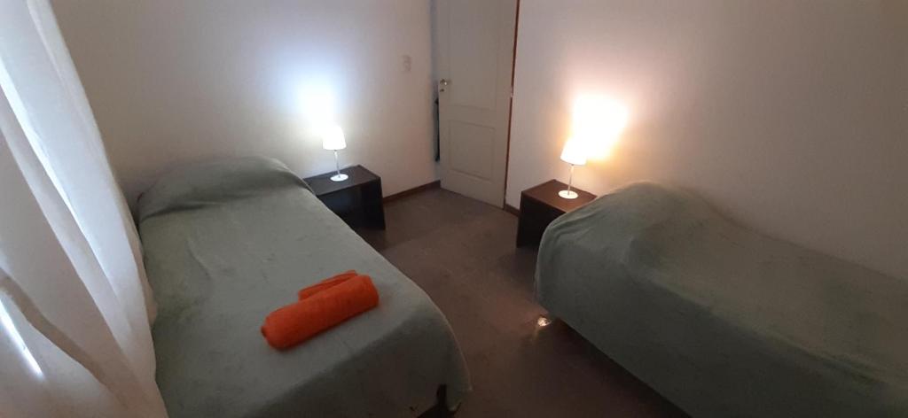 een kleine kamer met 2 bedden en 2 lampen bij DEPARTAMENTO EN LA MONTAÑA in Ushuaia