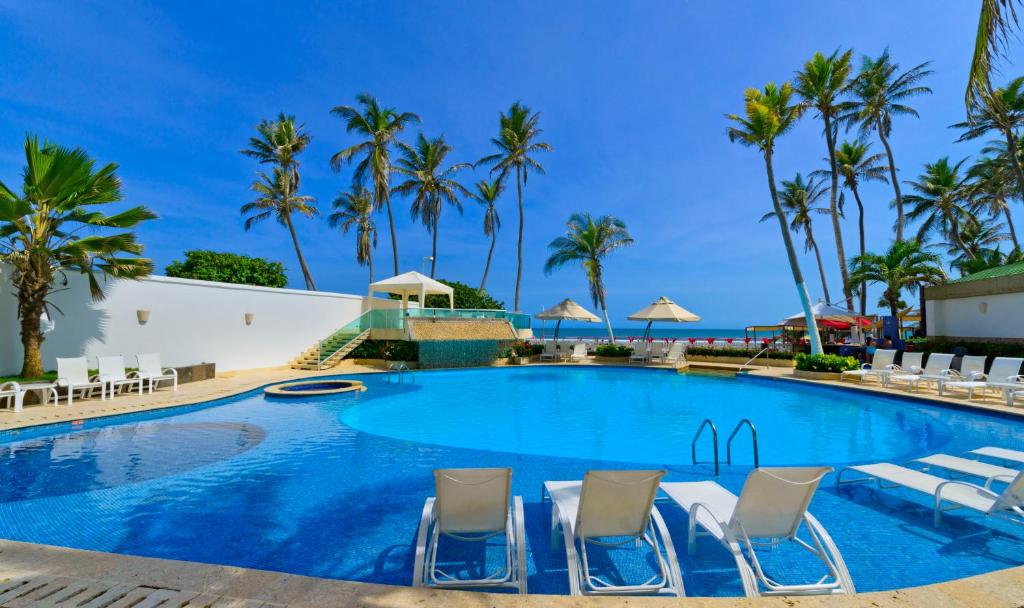 a large swimming pool with chairs and palm trees at Hotel Dann Cartagena in Cartagena de Indias